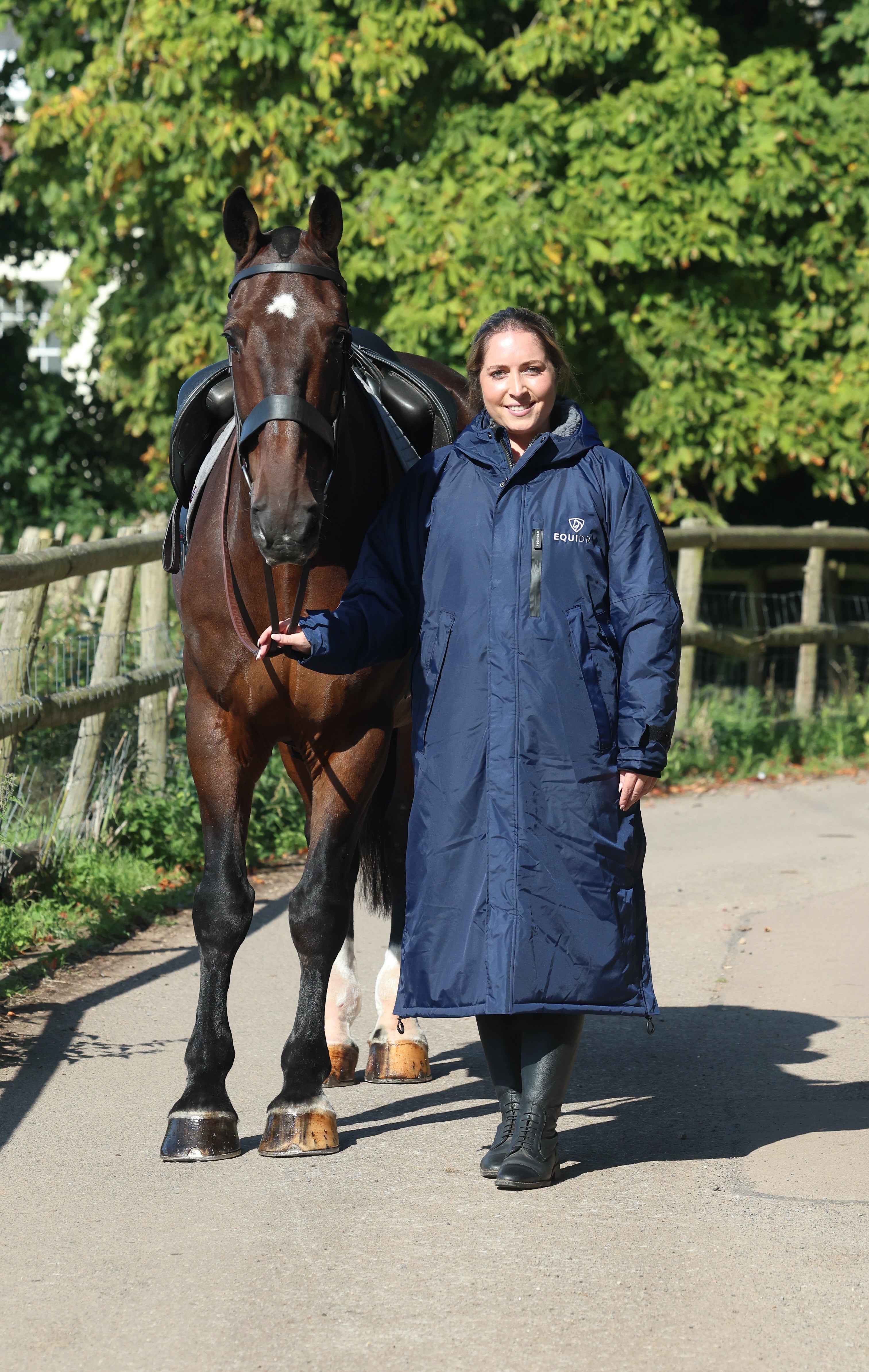EQUIDRY women's long waterproof horse riding coat in navy/charcoal modelled by rider with horse