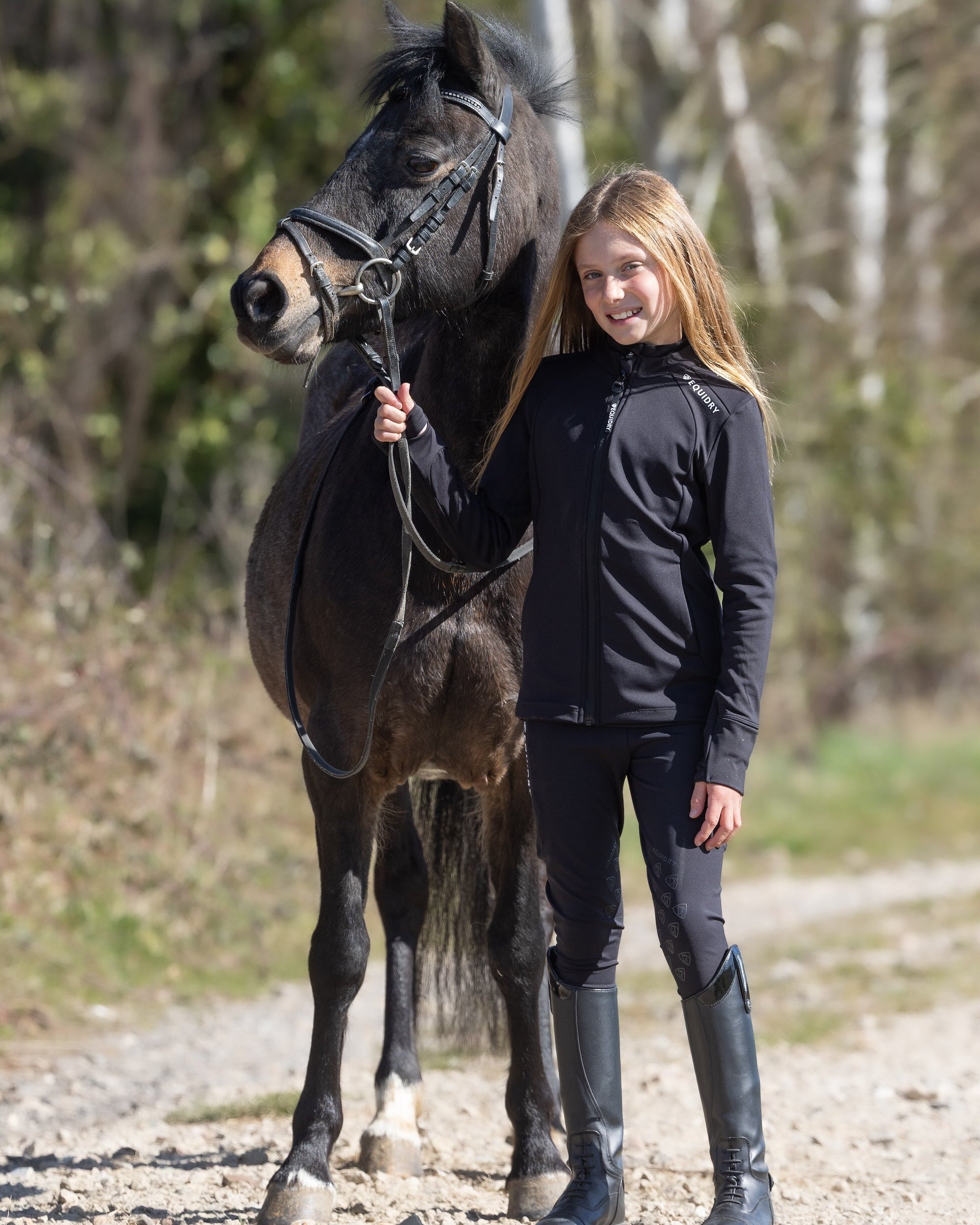 Child rider with horse in Equidry water-repellent black equestrian leggings with knee grip. #equestrian #leggings #horse