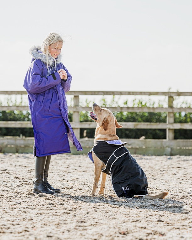 EQUIDRY Evolution Lux children's Warm Waterproof Winter Horse Riding Coat Thick Fleece Lining with Faux Fur Trim Hood being shown in purple by girl playing with dog in matching dog coat