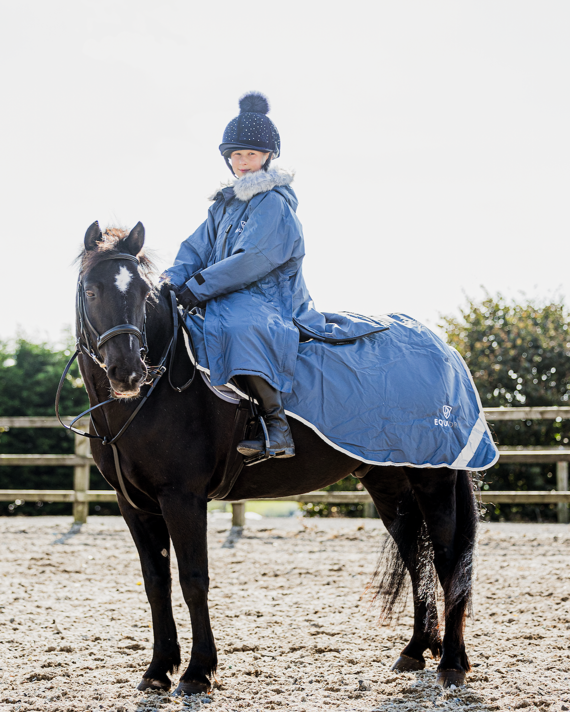 EQUIDRY Evolution Lux children's Warm Waterproof Winter Horse Riding Coat Thick Fleece Lining with Faux Fur Trim Hood being shown in steel blue on horse