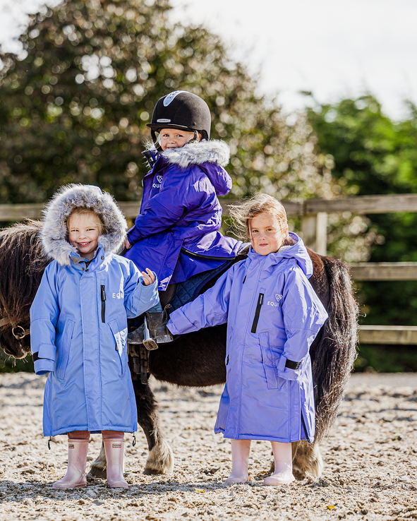 EQUIDRY Evolution Lux children's Warm Waterproof Winter Horse Riding Coat Thick Fleece Lining with Faux Fur Trim Hood being shown in purple, sky blue, charcoal/pale pink with kids on horse
