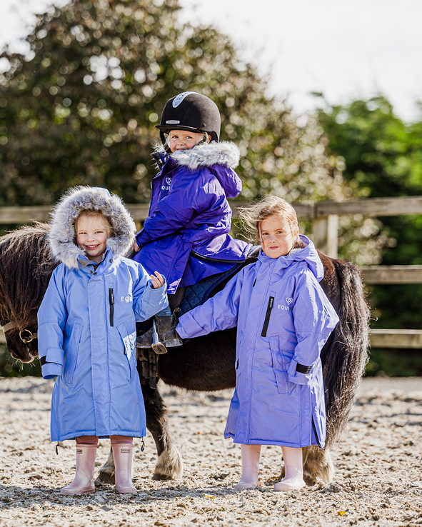 EQUIDRY Evolution Lux children's Warm Waterproof Winter Horse Riding Coat Thick Fleece Lining with Faux Fur Trim Hood being shown in purple, sky blue, charcoal/pale pink with kids on horse