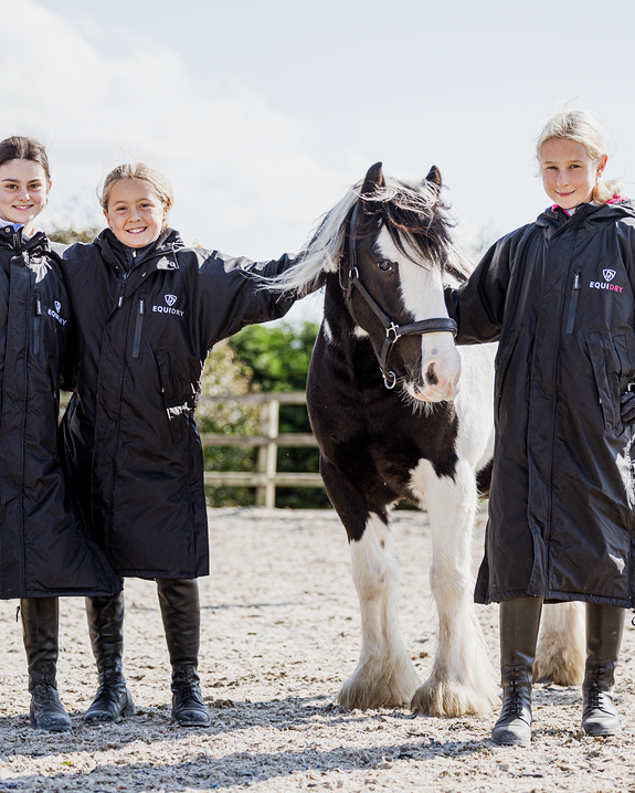 Equidry Children's Riding Coats: Three kids with horse in black waterproof Equidry Evolution Thin Fleece equestrian apparel.