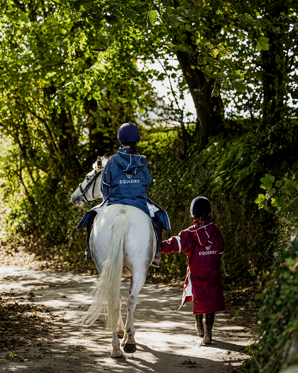 EQUIDRY waterproof horse riding raincoat thin fleece pro ride reflective kids plum and steel blue children's jackets rider on horse back view