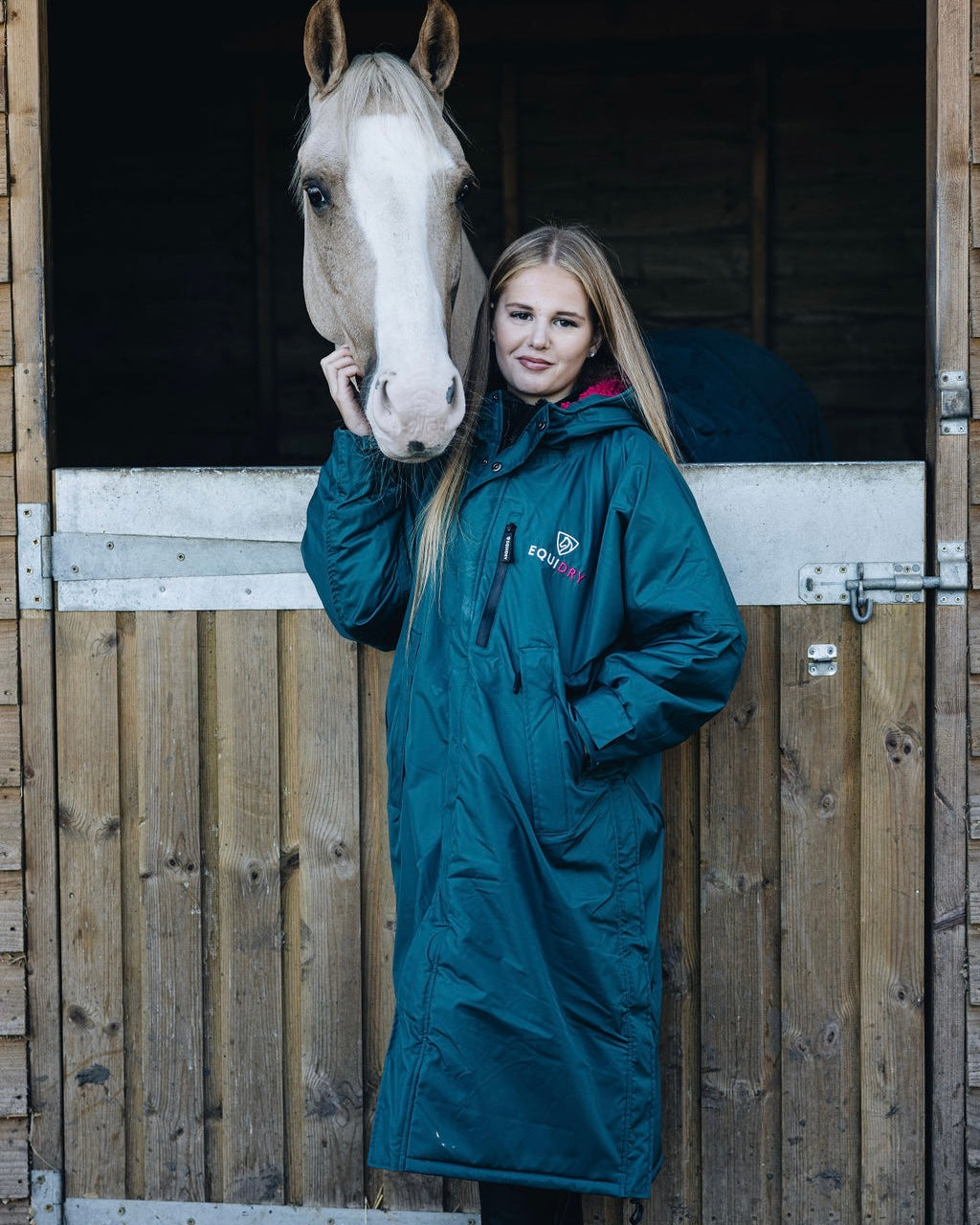 EQUIDRY coat: Woman in teal riding coat with horse. Waterproof & fleece-lined equestrian outerwear.