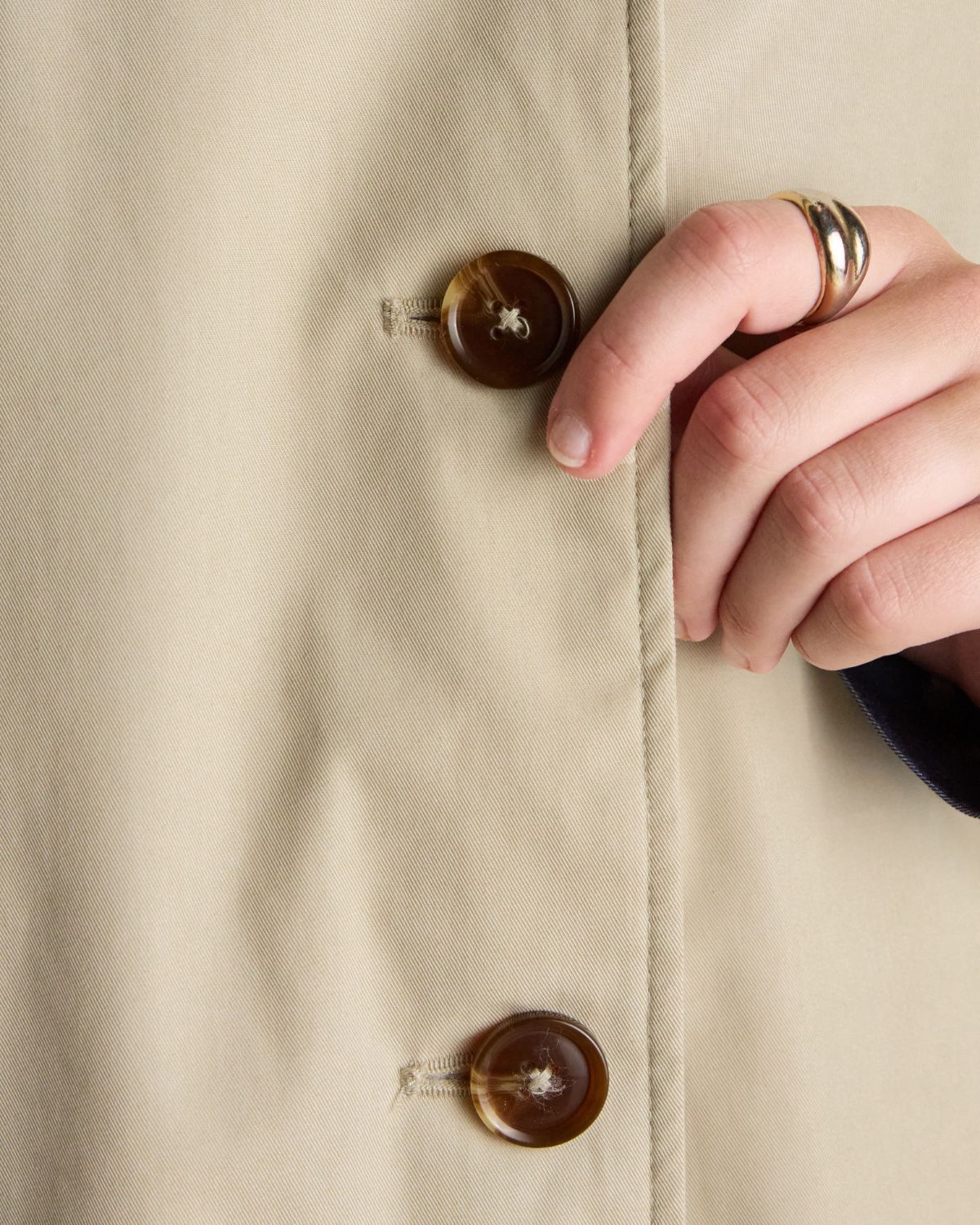 JOULES Rainmore beige waterproof raincoat with button detail. Stylish rainwear with brown buttons and hand detail with gold ring.
