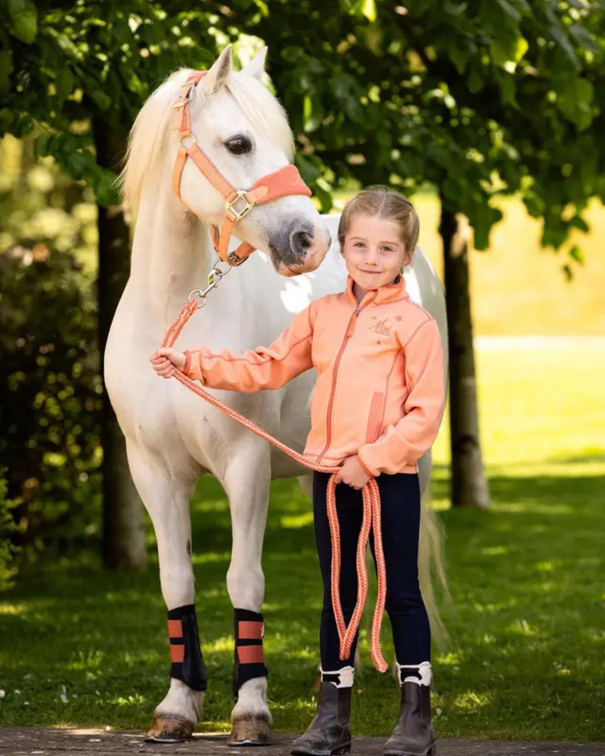 Girl with white pony wearing LeMieux MINI apricot brushing boots. Pony riding, equiflair.