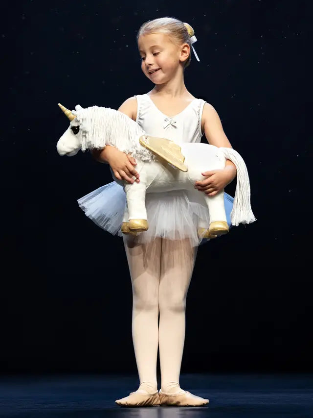 Ballerina Holding Unicorn Toy at Dance Recital: Young Girl in Tutu with Stuffed Animal, Stage Performance