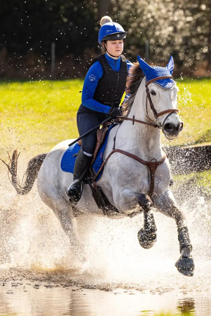 Horse and Rider in Action: LEMIEUX Benetton Blue Saddle Pad on Grey Horse Splashing Through Water | Equiflair