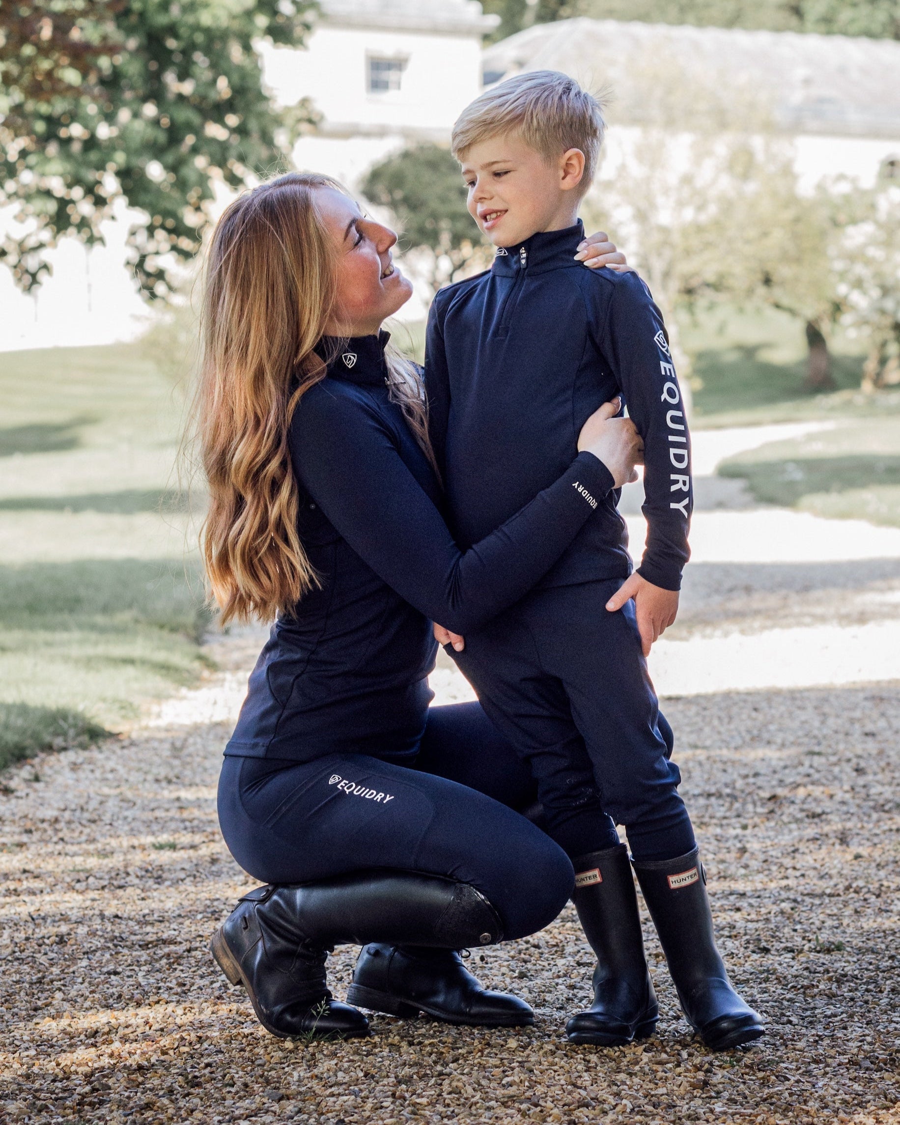 Equidry Equestrian Base Layers: Mother and son in matching navy riding outfits outdoors. Children's water repellent layer.