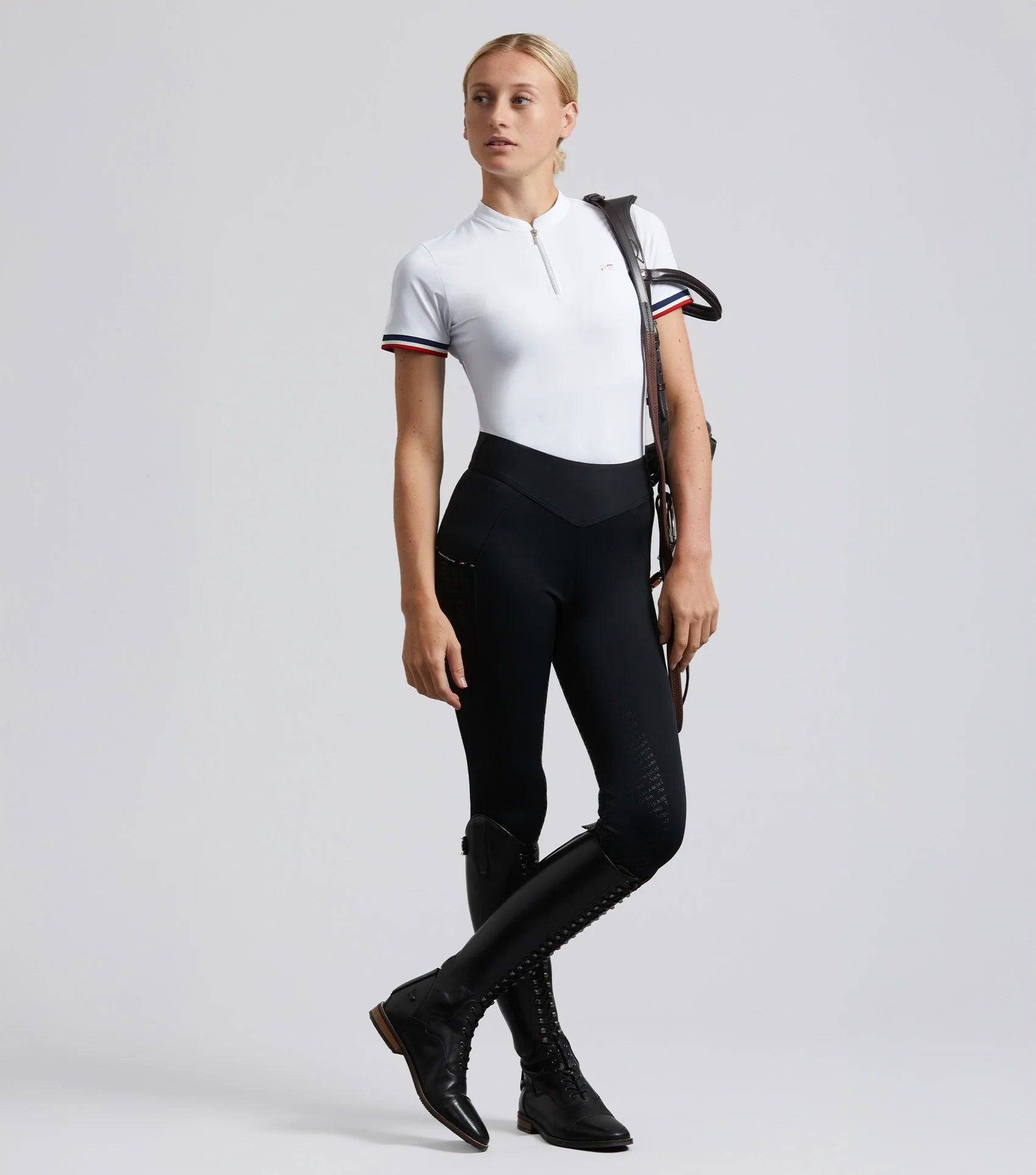 Woman in Premier Equine Aporia riding tights jet black equestrian apparel. Black riding pants, high waist, full seat silicone gel.