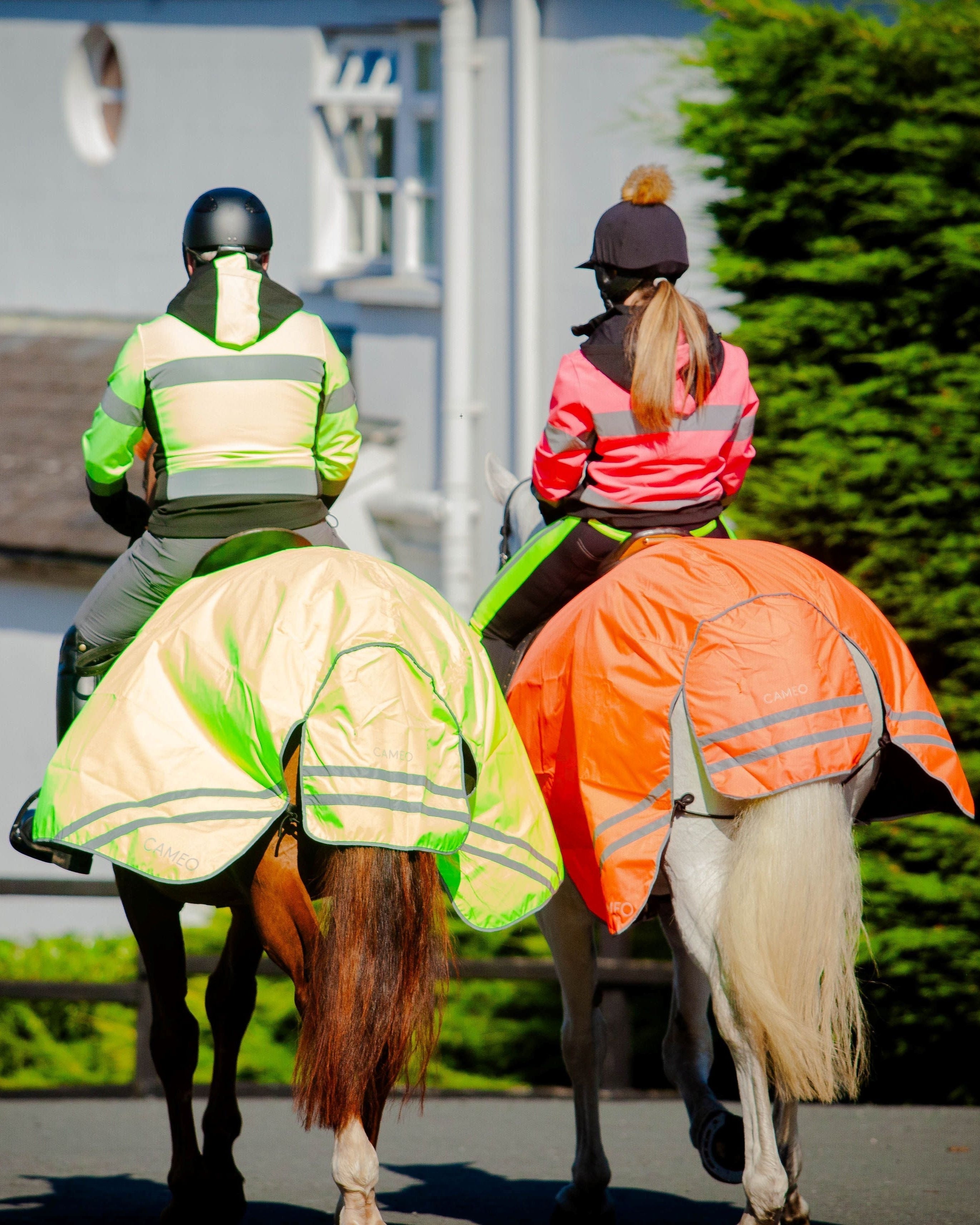 Two horses with riders in CAMEO hi-viz safety jackets. Riding safely with Equiflair's hi-visibility gear.
