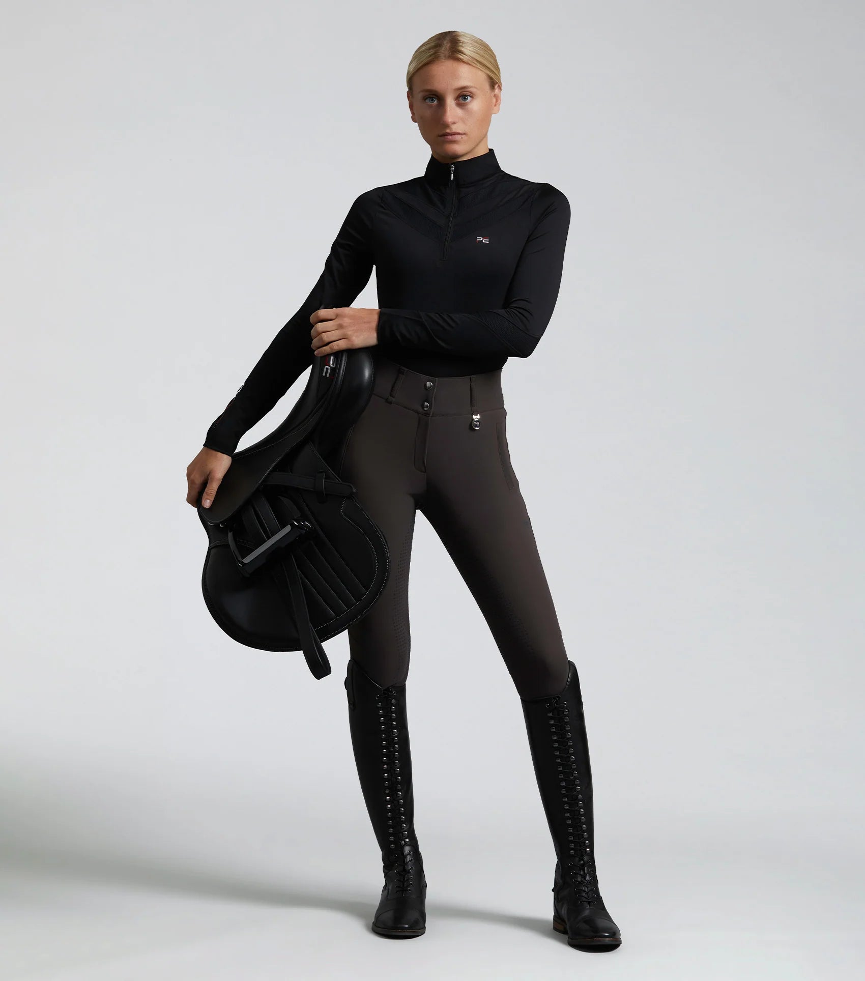 Equestrian Woman in Premier Equine Riding Gear: Carapello Breeches, Riding Top, and Boots. Full Seat Gel Breeches for Women