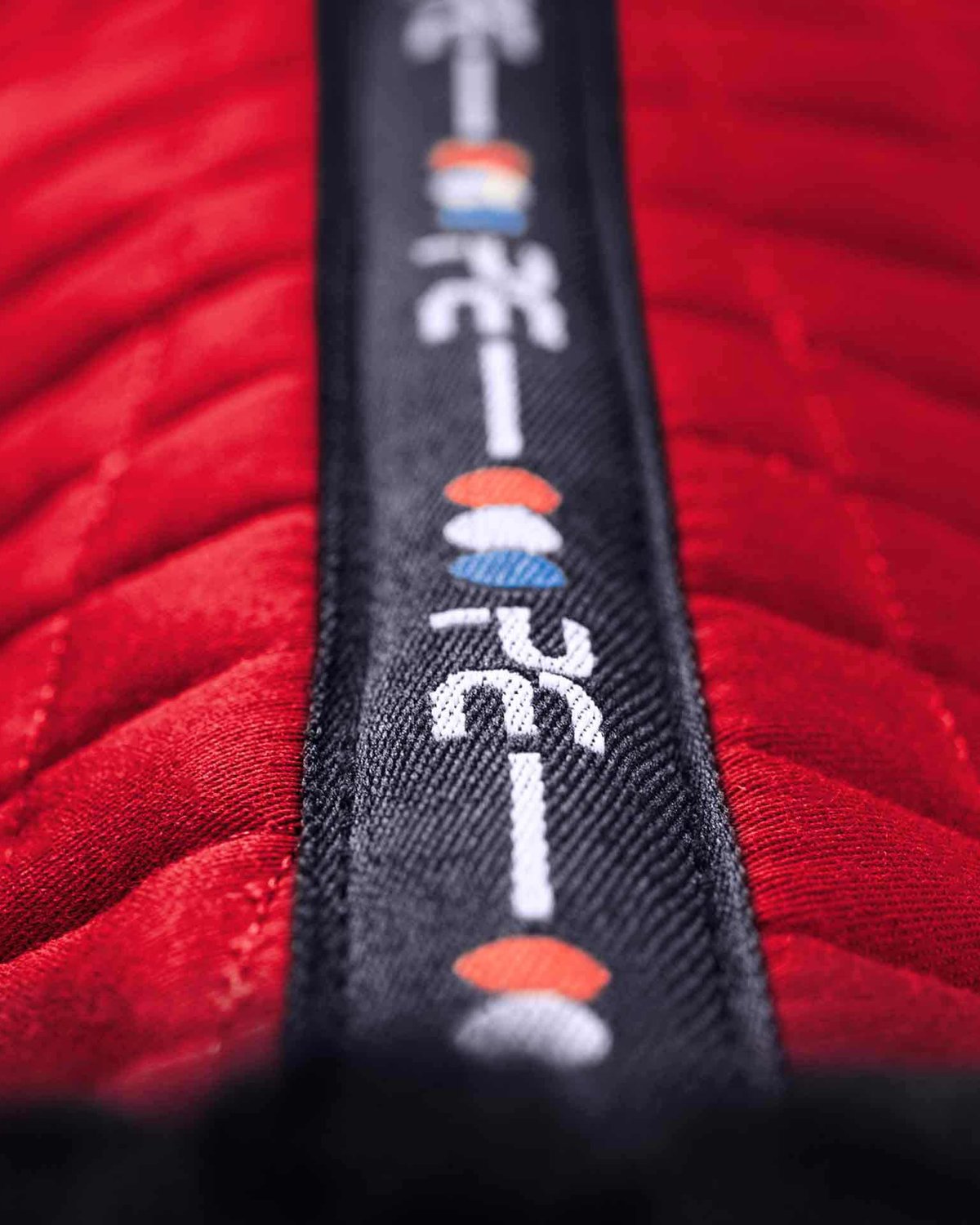 Premier Equine Merino Wool Saddle Pad GP/Jump Numnah - Red/Navy. Close up on spine design with logo.