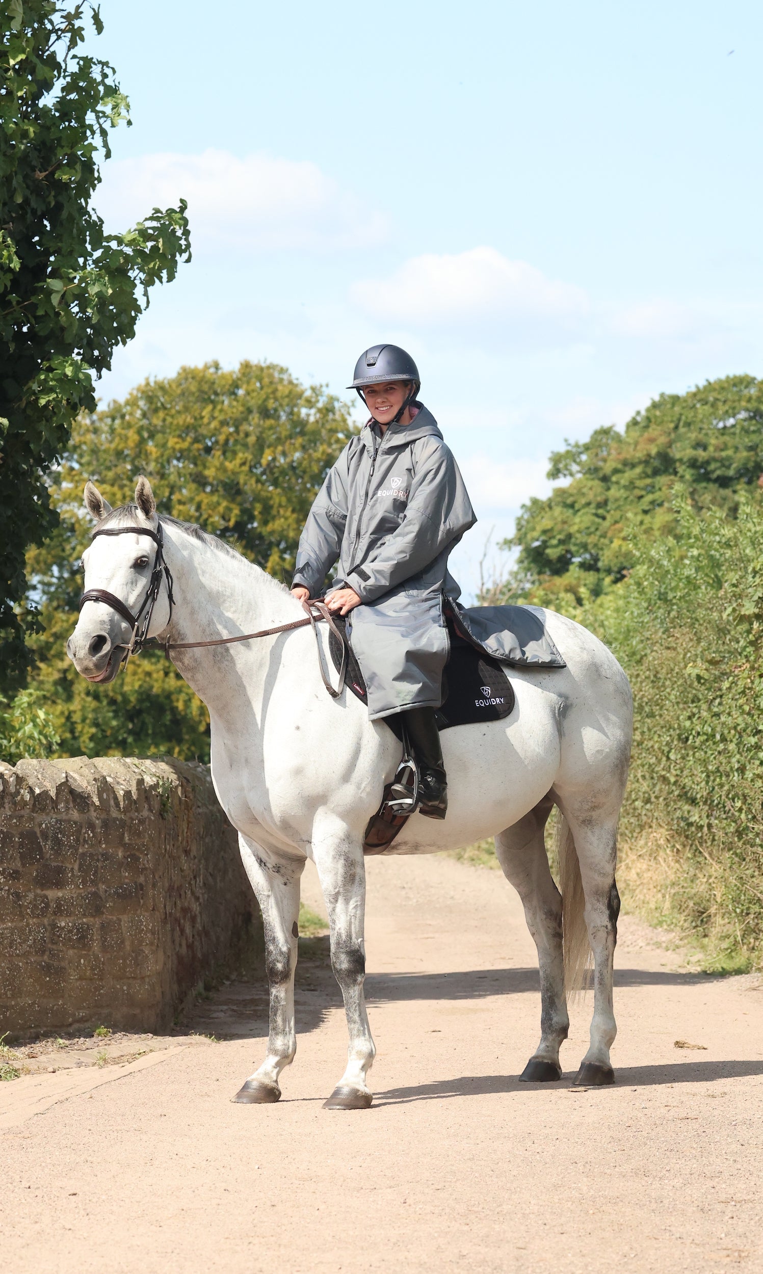 EQUIDRY waterproof horse riding raincoat All Rounder Original thick fleece Women's Charcoal/Pale Pink side view rider on horse