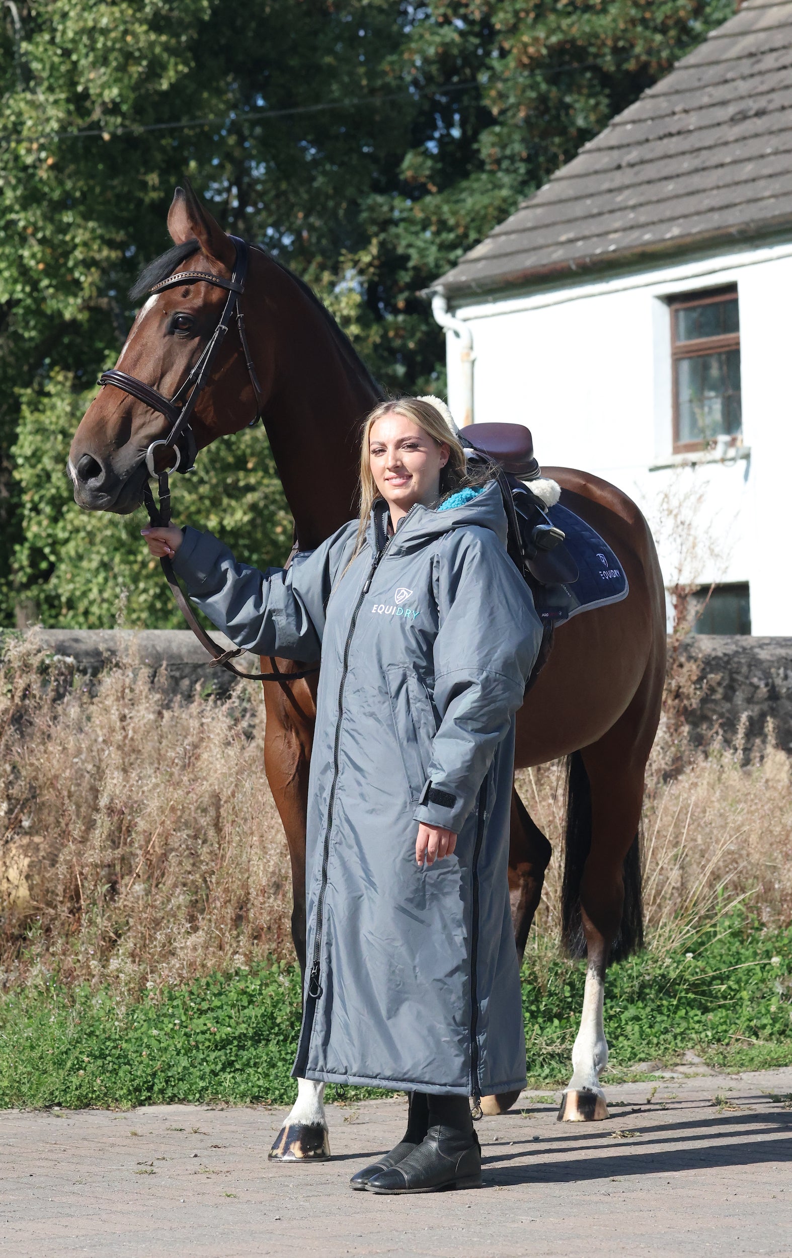 EQUIDRY waterproof horse riding raincoat All Rounder Original thick fleece Women's Charcoal/Turquoise rider stood with horse full view