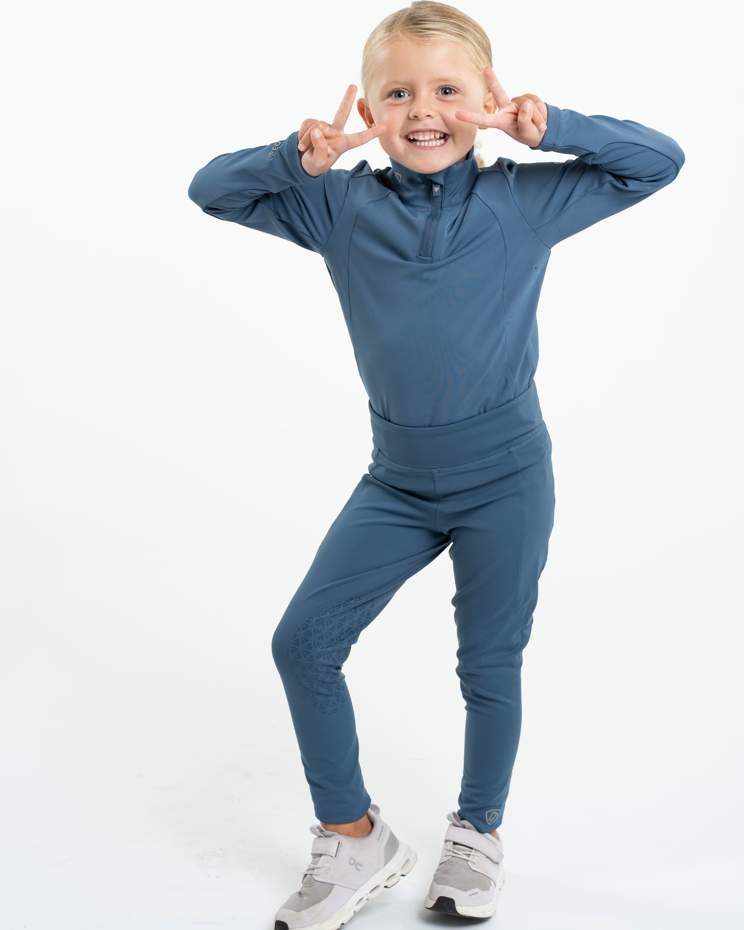 Girl in EQUIDRY Kids Riding Leggings: Steel Blue Equestrian Apparel with Knee Grips, Water Repellent, and Comfortable…