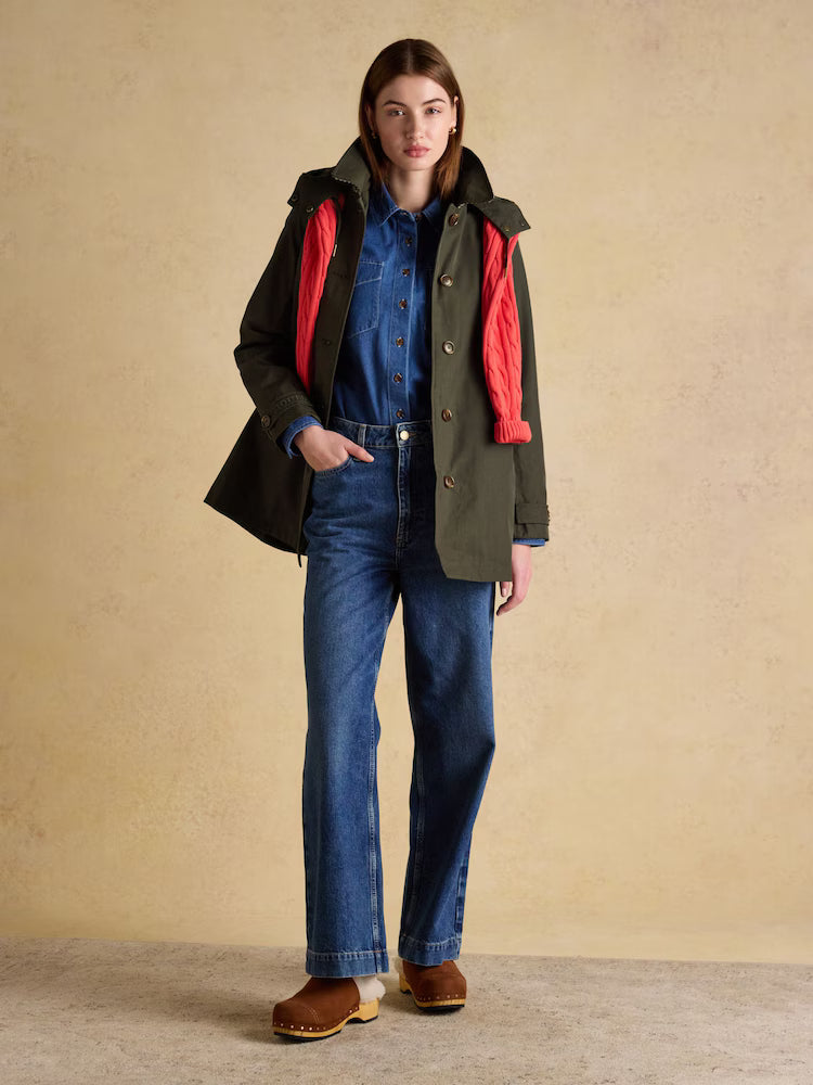 Woman in Joules Khaki Green Waterproof Raincoat with Hood and Red Scarf. Stylish Women's Outerwear.