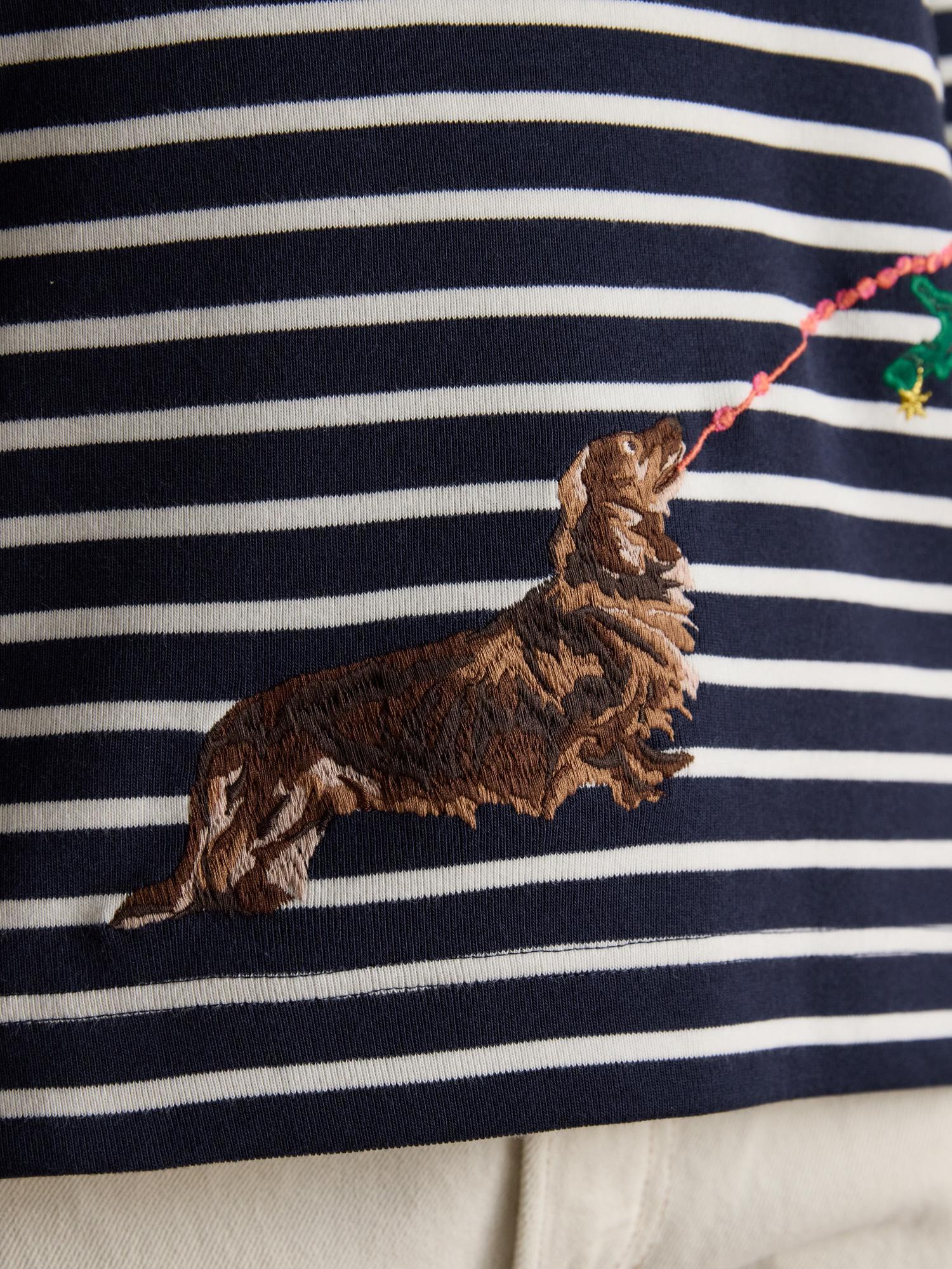 JOULES Festive Dog Breton Top: Navy striped boat neck with a dog embroidery near a christmas tree.
