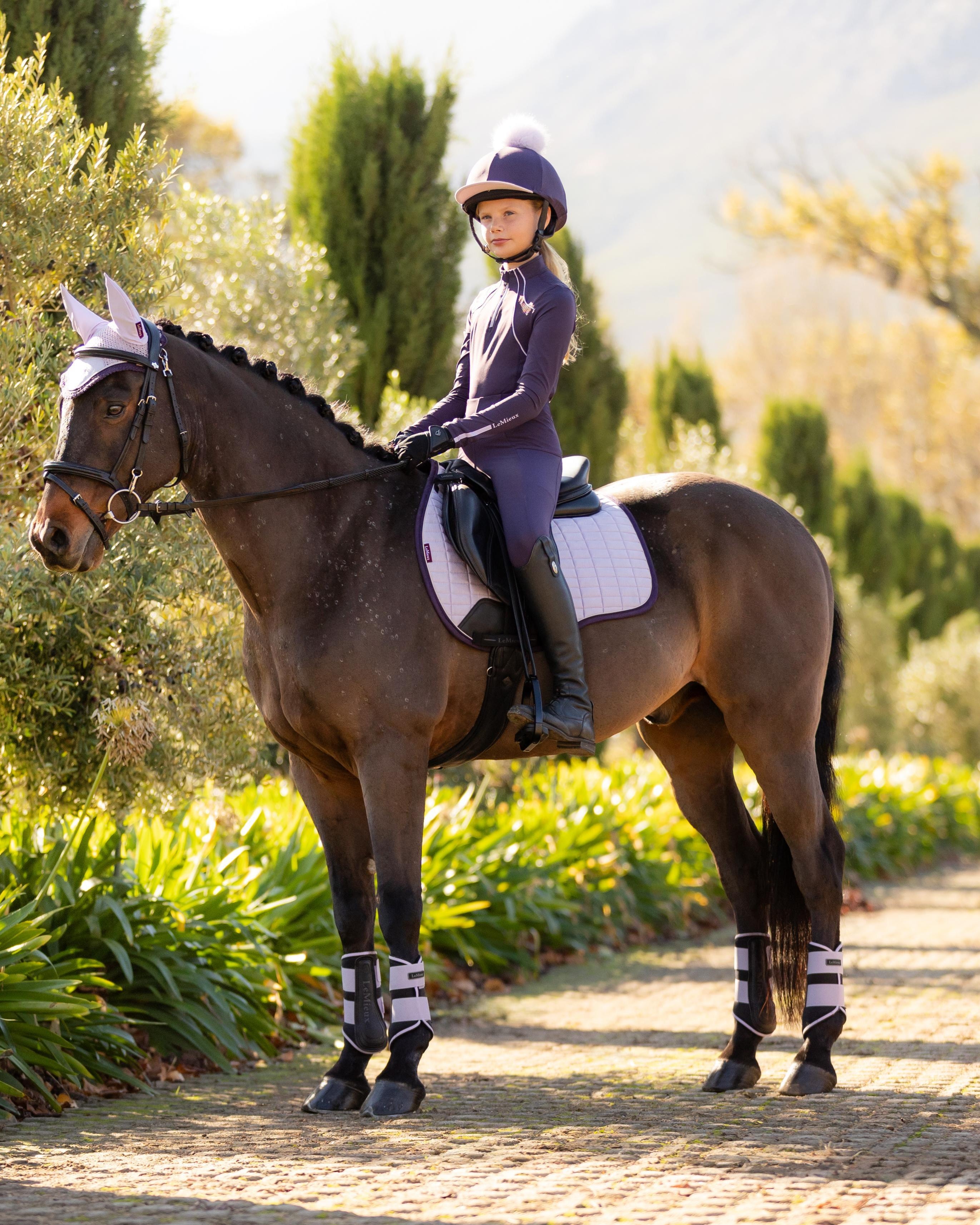 Girl riding horse in Lemieux Lilac Suede GP Square Saddle Pad. Equestrian Sportswear & Horse Riding Equipment from Equiflair.