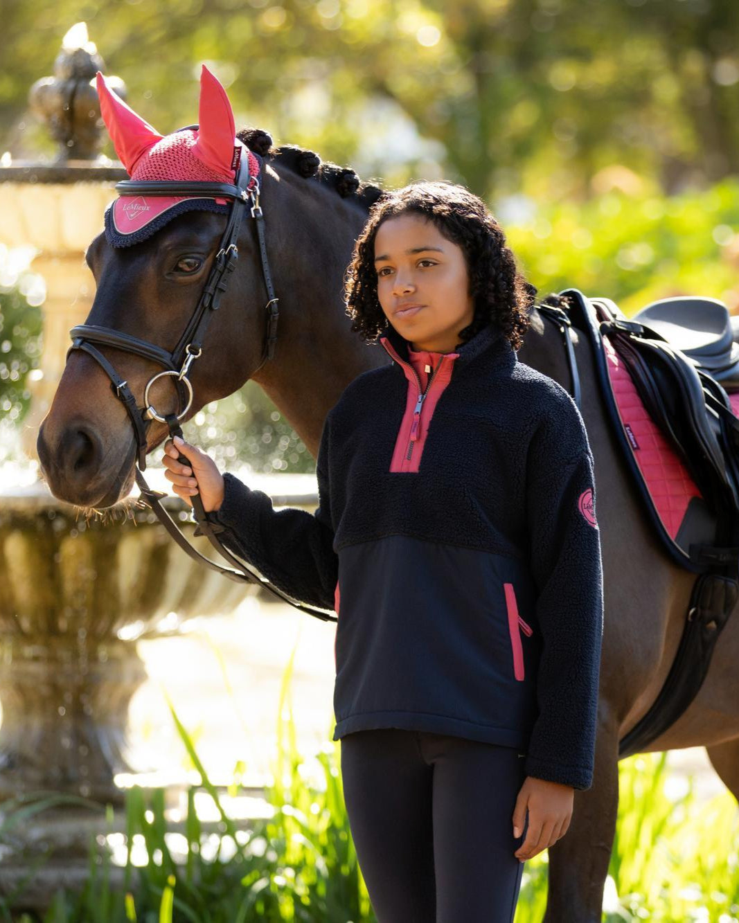 Young rider with horse wearing LeMieux navy teddy fleece equestrian top. Cozy winter riding apparel by Equiflair.
