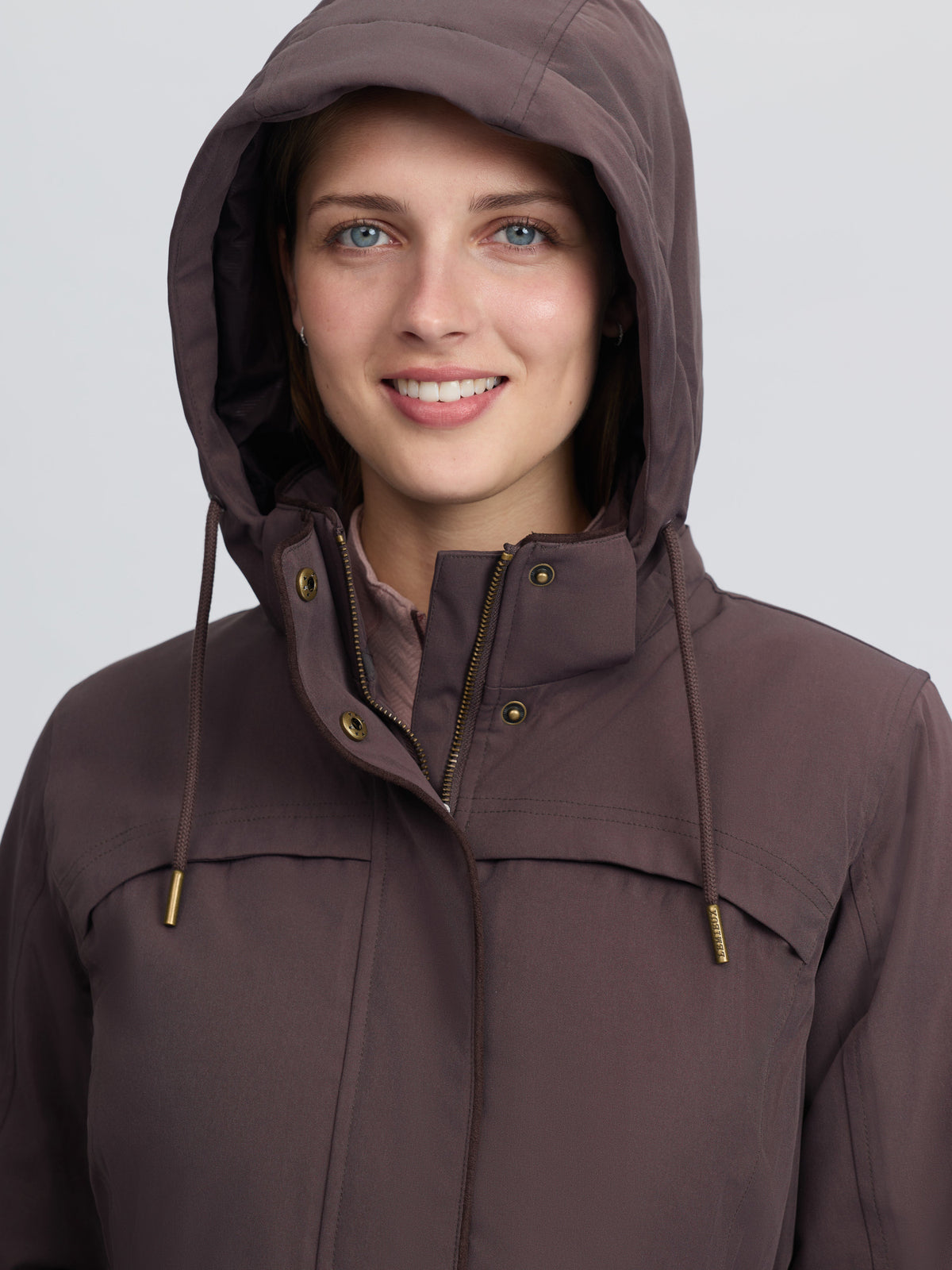 Woman wearing a brown LEMIEUX HERITAGE BEATRICE waterproof hooded country coat
