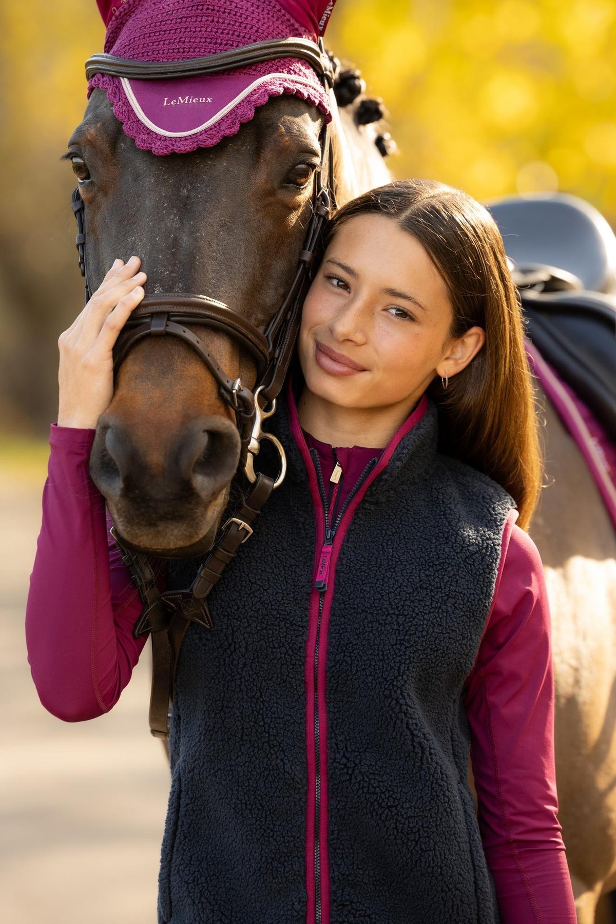 Young rider with horse, wearing navy LeMieux gilet and purple bonnet