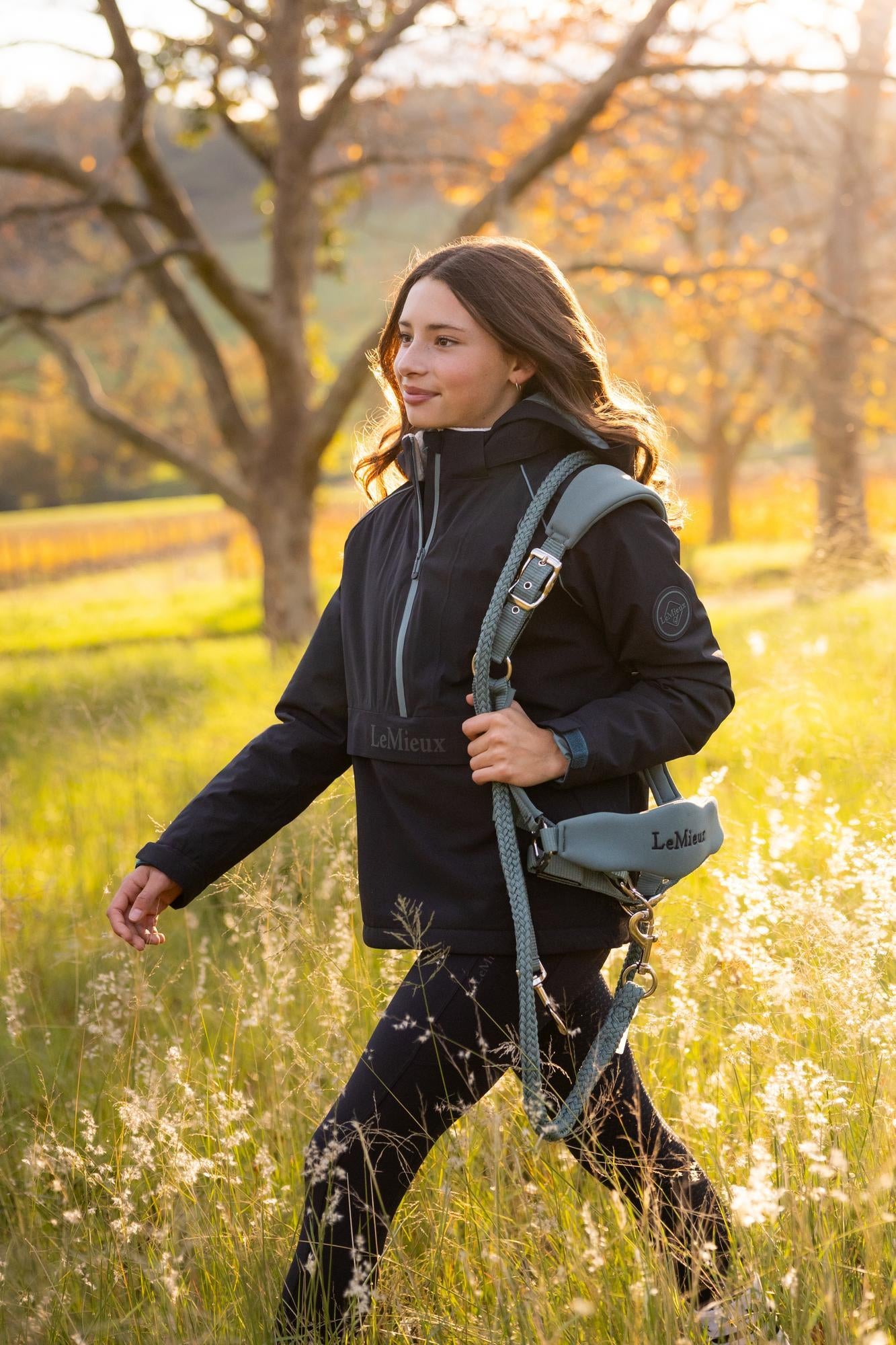 Young rider in navy LeMieux waterproof anorak walking in field