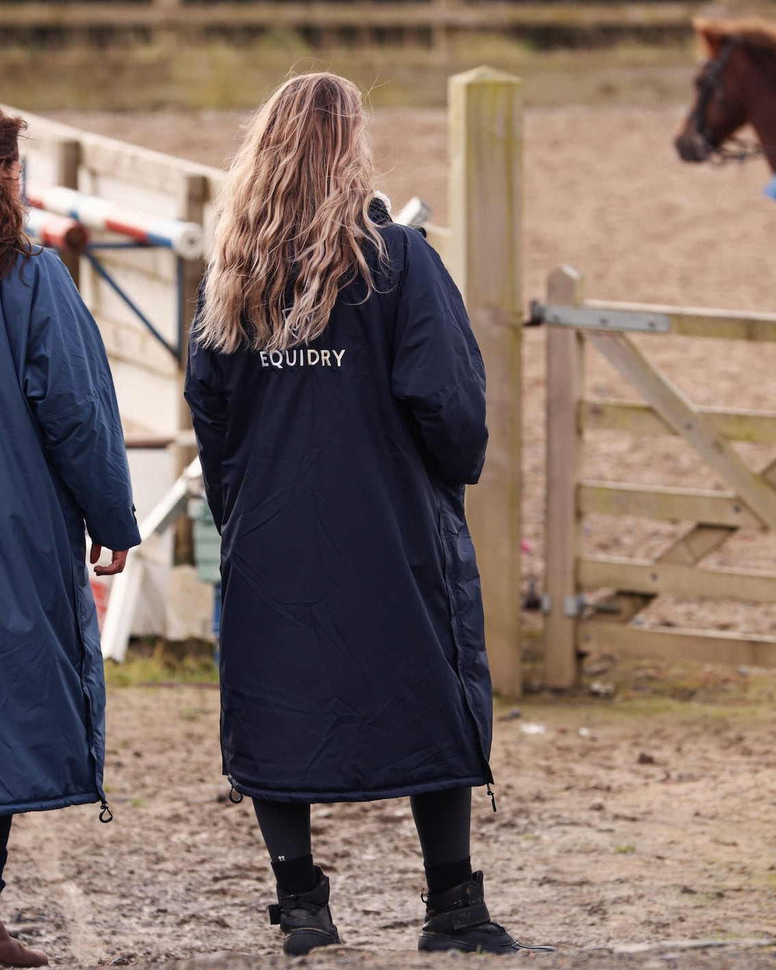 EQUIDRY women's long waterproof horse riding coat in navy/cream mums stood spectating riding lesson by arena, back of coats