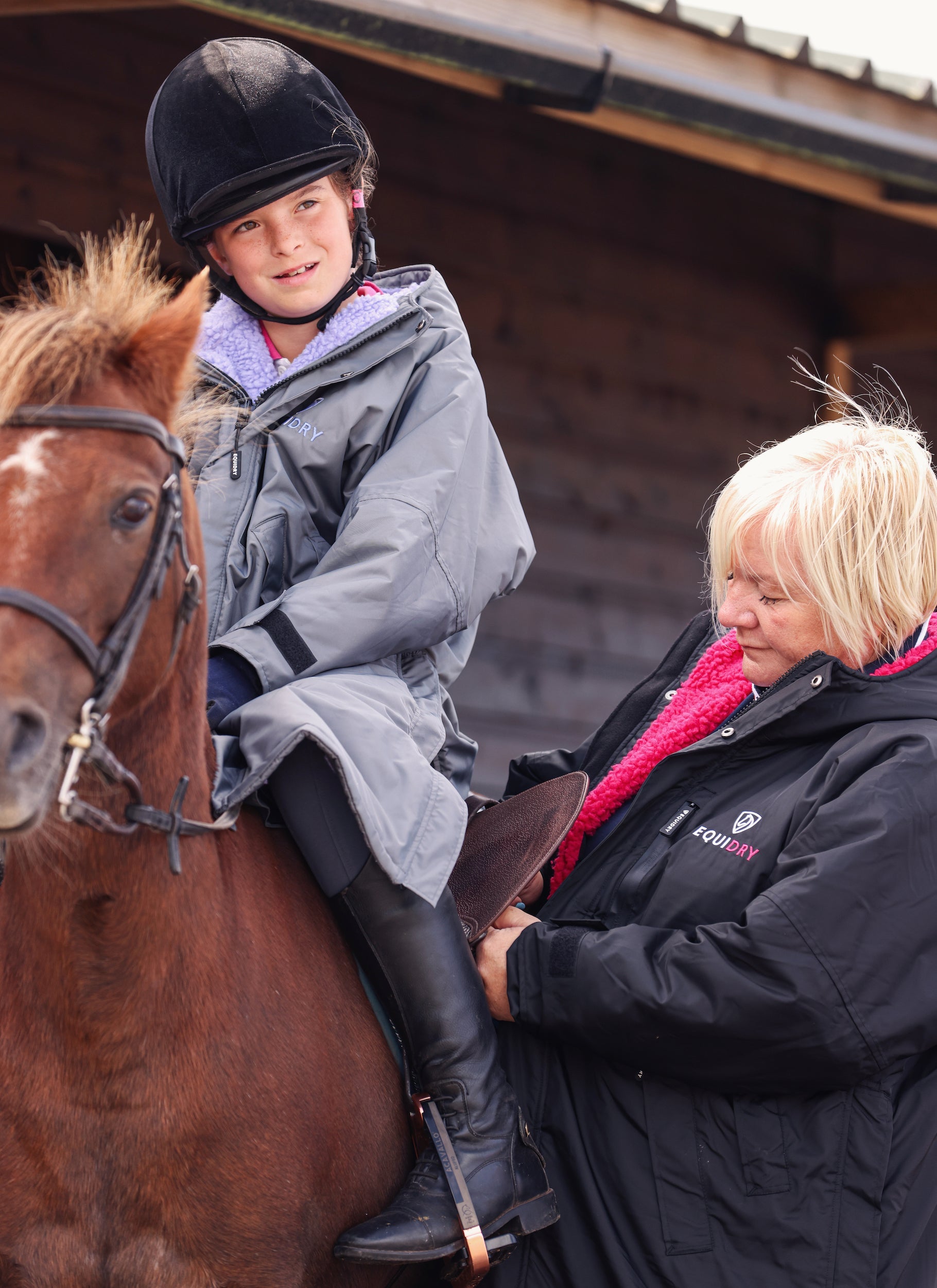 EQUIDRY women's long waterproof horse riding coat in black/peacock pink modelled by pony club instructor
