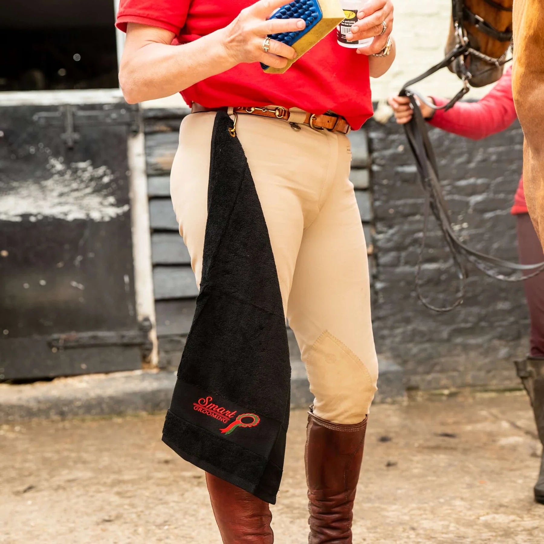Equiflair Smart Grooming Handy Towel: Black cotton horse grooming towel with brass clip attached to rider's breeches.