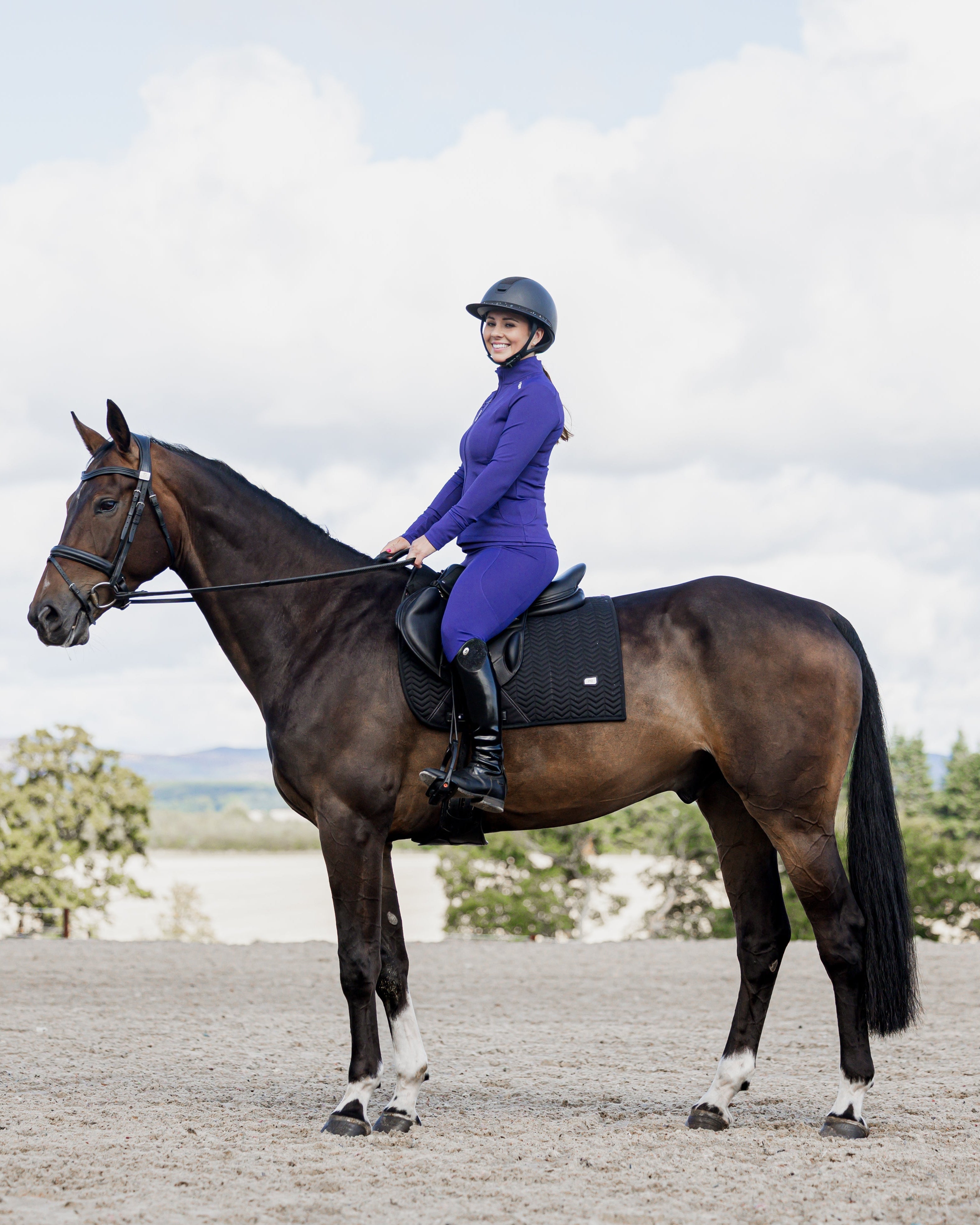 Equestrian in purple EQUIDRY water-repellent leggings on horseback. Full seat for secure horseback riding.