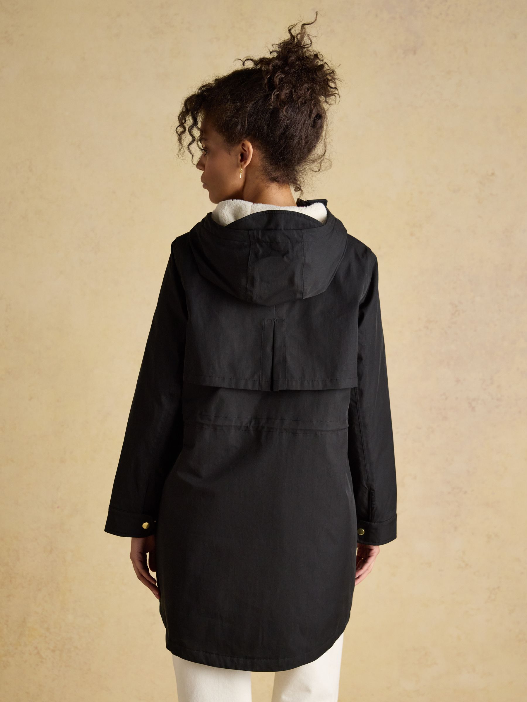 Joules black waterproof fleece lined raincoat with hood - model on beige background