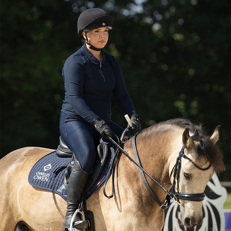 Equestrian rider wearing Charles Owen EQX Phoenix skull hat in black and rose gold. Horse riding safety gear by Equiflair.