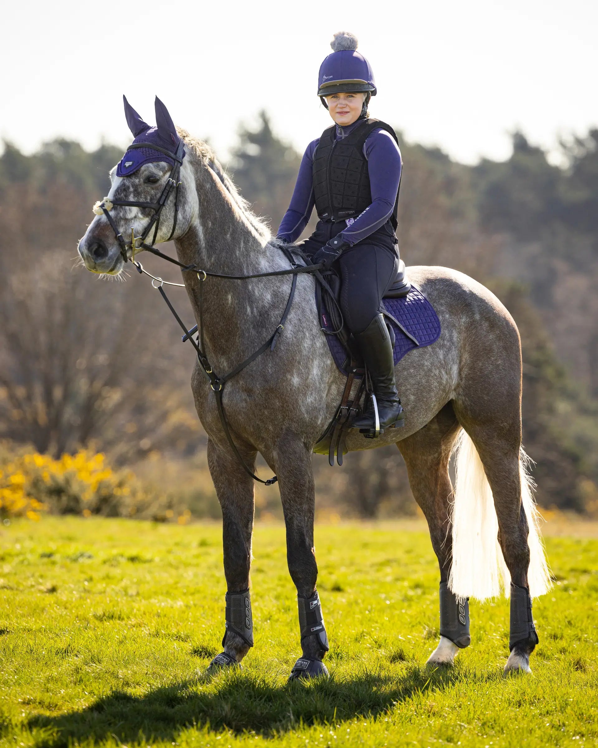 Equestrian rider on horse with LeMieux Ink Blue Suede GP Square saddle pad, Equiflair shop. Horse riding equipment.