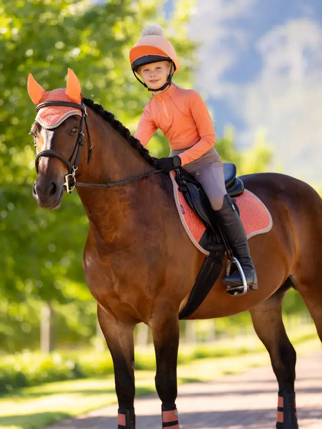 Young girl equestrian in apricot LeMieux gear: horse riding outfit, helmet & tack. Stylish horse riding look by Equiflair.