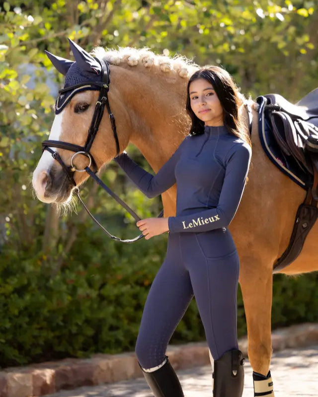 Young equestrian rider in Lemieux Orla pull ons dusk blue riding leggings with horse and gear by Equiflair.