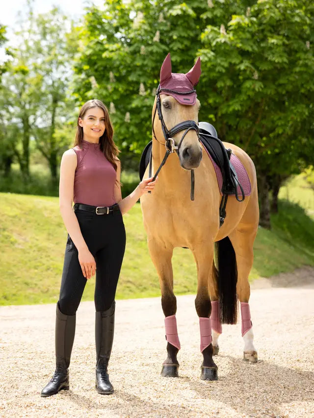 Equestrian girl with horse wearing LeMieux Rosewood sleeveless top, black riding pants & boots. Horse in Rosewood fly bonnet and leg wraps