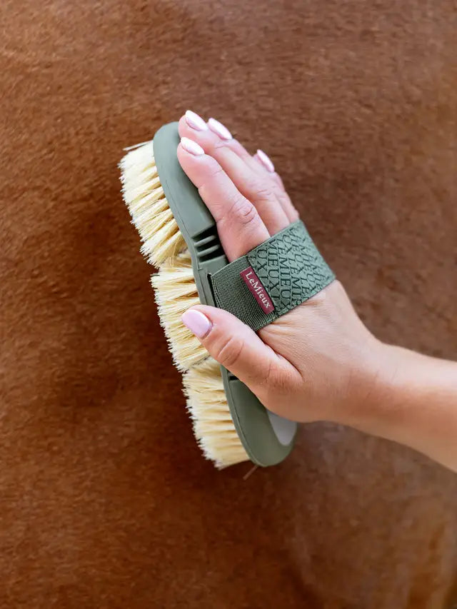 LeMieux Flexi Scrubbing Brush: Horse Grooming & Care - Hand using brush on horse coat.