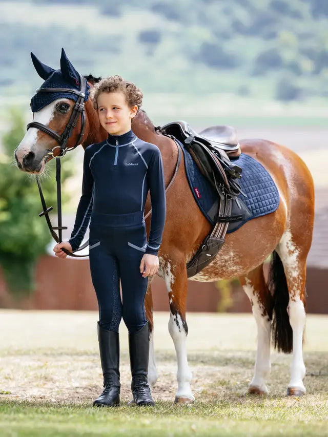 Young rider with horse wearing LEMIEUX MINI SUEDE CLOSE CONTACT SQUARE NAVY saddle pad. Equestrian lifestyle.