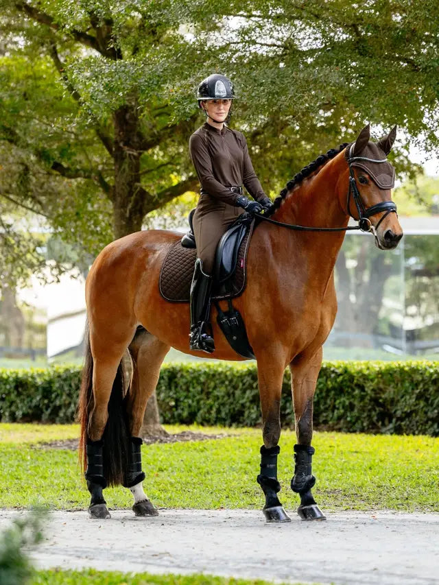 Woman in brown riding attire on a brown horse wearing LeMieux Brilliance Dressage Square saddle pad