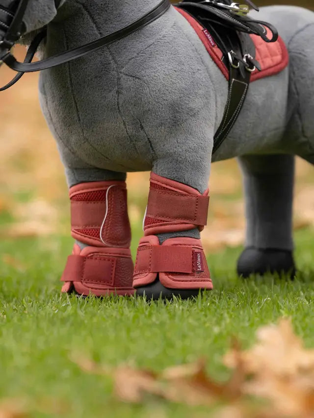 LeMieux russet mesh brushing boots on a grey toy pony standing in grass