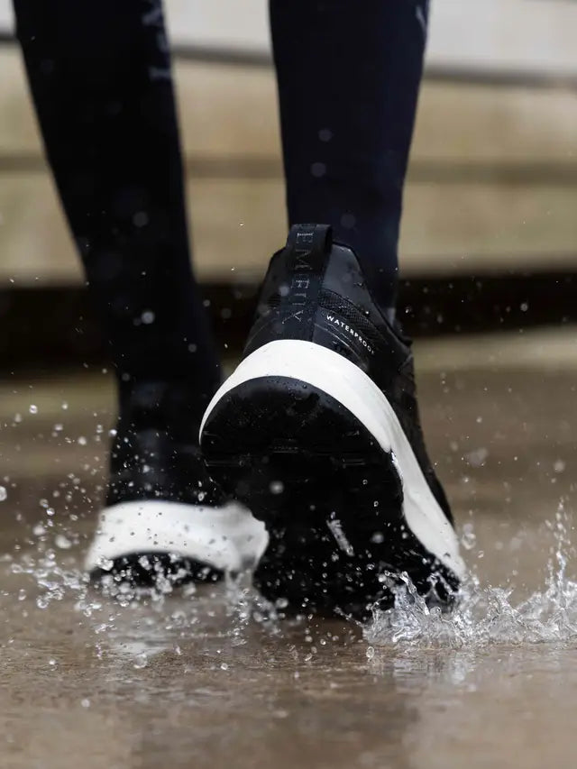 Black waterproof trainers splashing in water, showing "EMENY" and "WATERPROOF" labels.