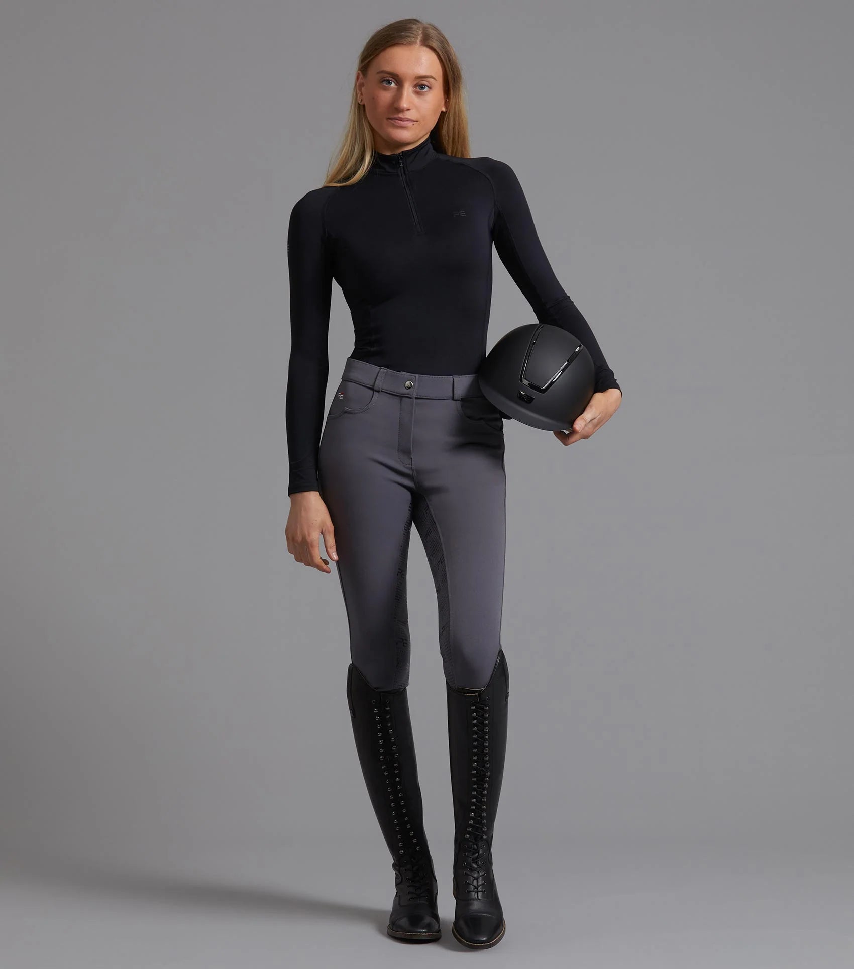 Equestrian: Lady in Black Technical Riding Top with Helmet & Riding Boots. PREMIER EQUINE OMBRETTA Style.