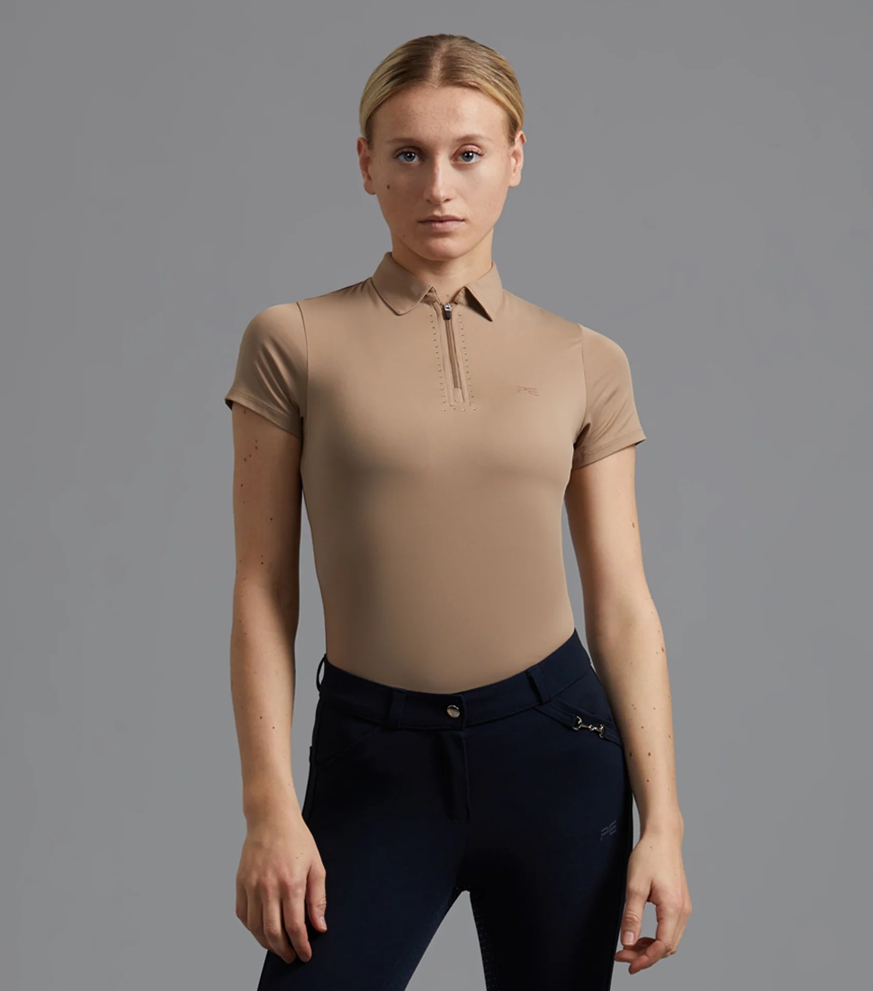 Premier Equine Scintillo Beige Riding Top. Woman in Equestrian Apparel, Navy Breeches. Short Sleeve, Lightweight.