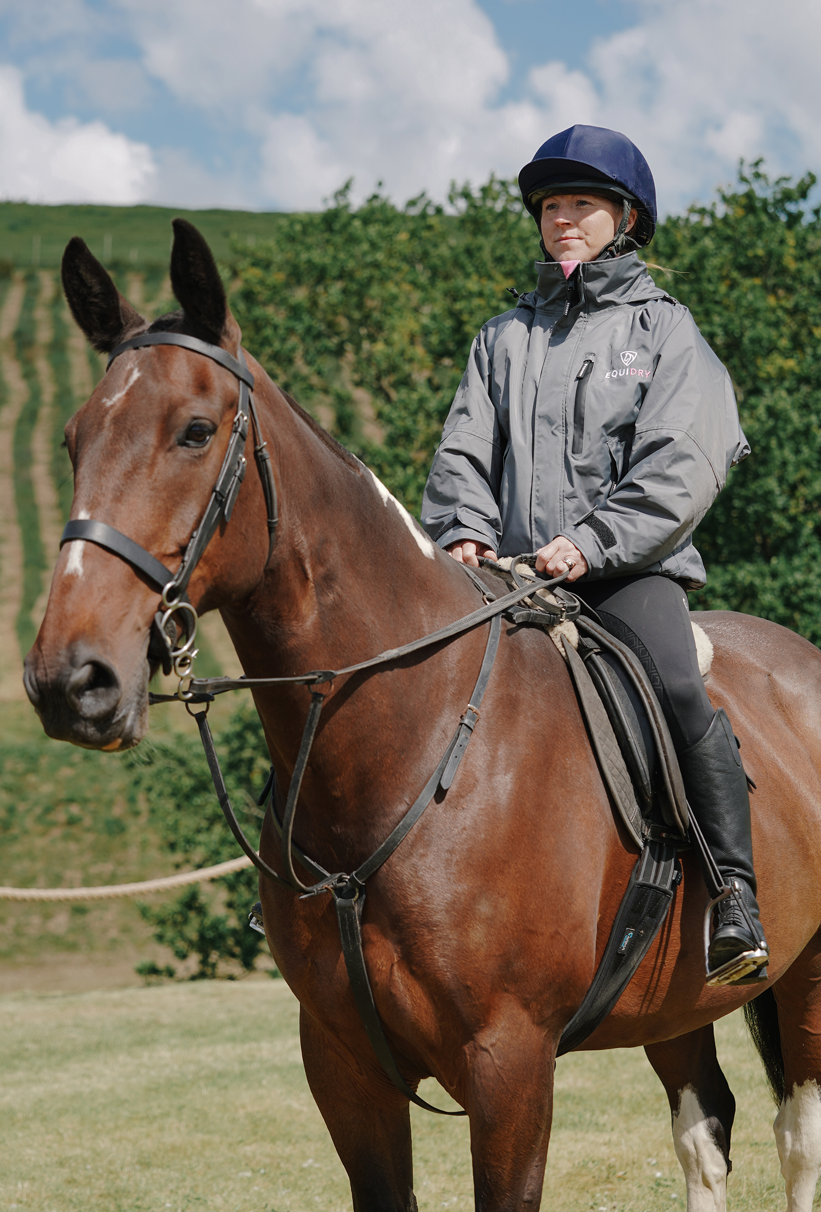 EQUIDRY women's waterproof short blouson style horse riding jacket in charcoal/penelope pink sat on horse