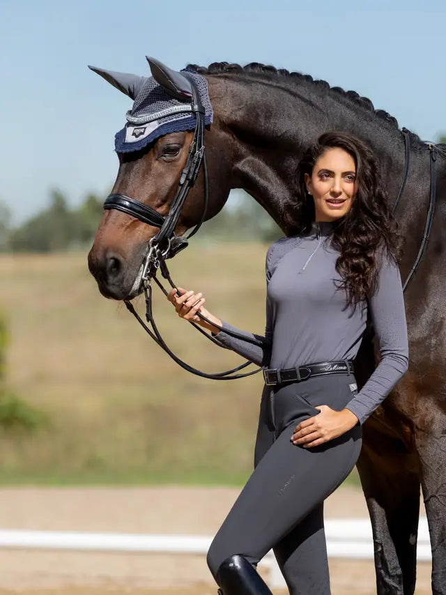 LeMieux Loire Fly Hood Twilight Grey. Woman standing next to horse wearing the fly hood. Equestrian fashion