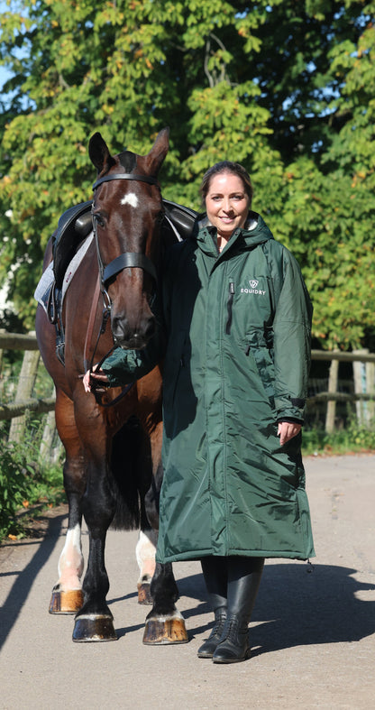Equidry waterproof horse riding coat. Woman in long green jacket with horse. Equestrian apparel for women