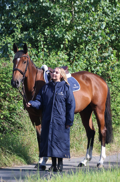 EQUIDRY women's long waterproof horse riding coat in navy/cream worn by rider walking with horse