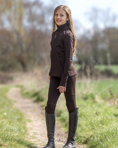 Child in EQUIDRY Brown Zip Up Top & Leggings. Riding Apparel by Equiflair. Long brown hair, outdoors, equestrian fashion. Water repellent.